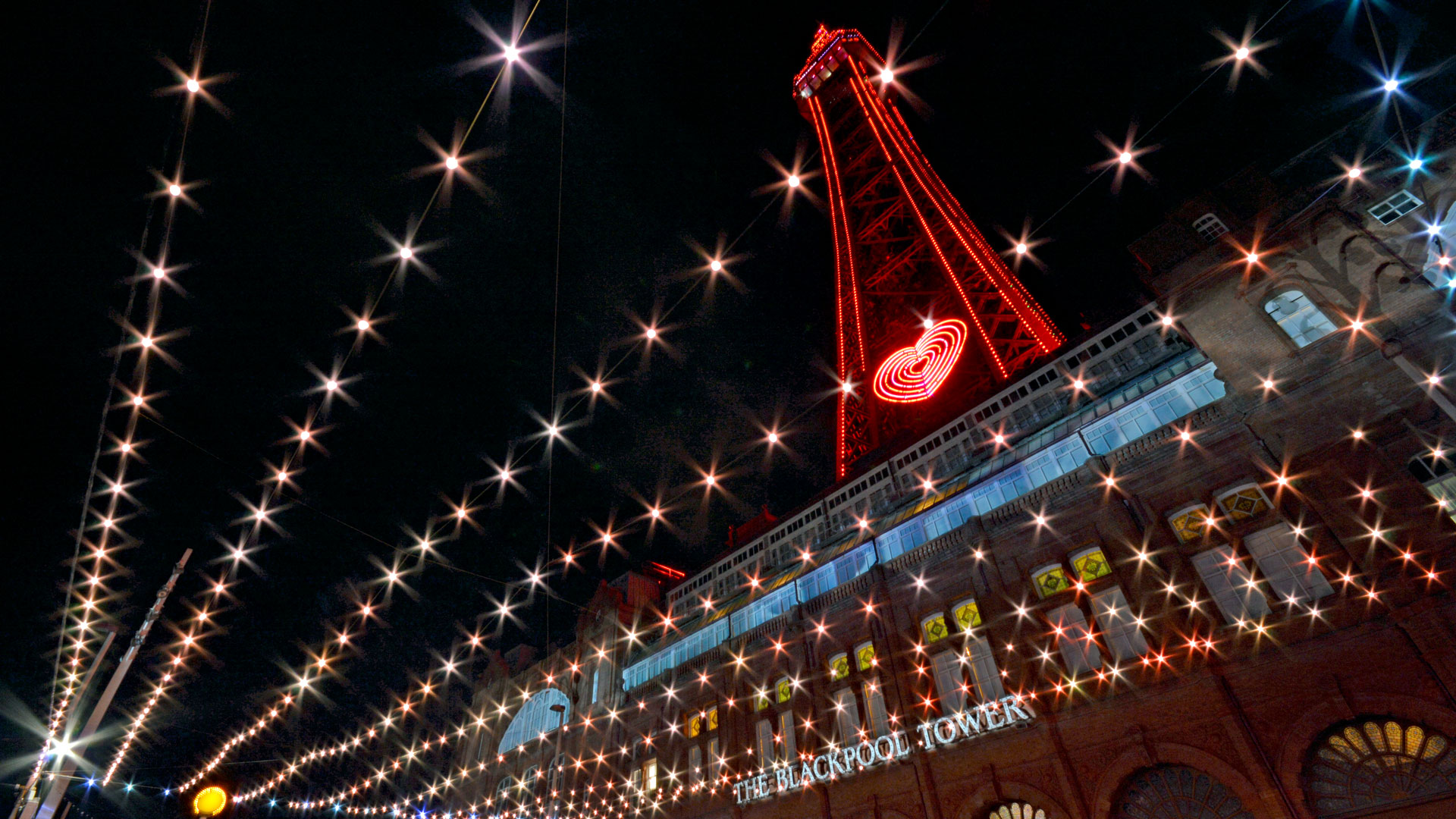 Warm white starburst canopy below the red-lit Blackpool Tower